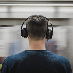 A man wearing Headphones stands clear amidst a blurry background