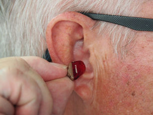 A Man adjusting his Hearing Aid