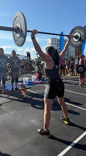 Woman lifting a barbell overhead at an outdoor competition