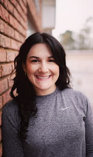 a smiling brunette woman in a gray long sleeve teeshirt