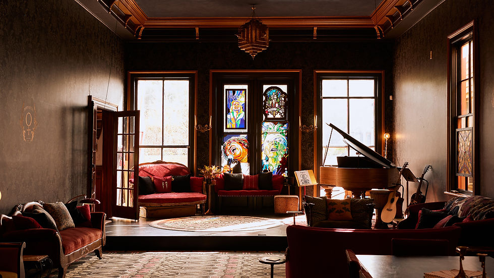 ballroom with a small stage, sofas, and large stained glass art pieces hanging in the windows