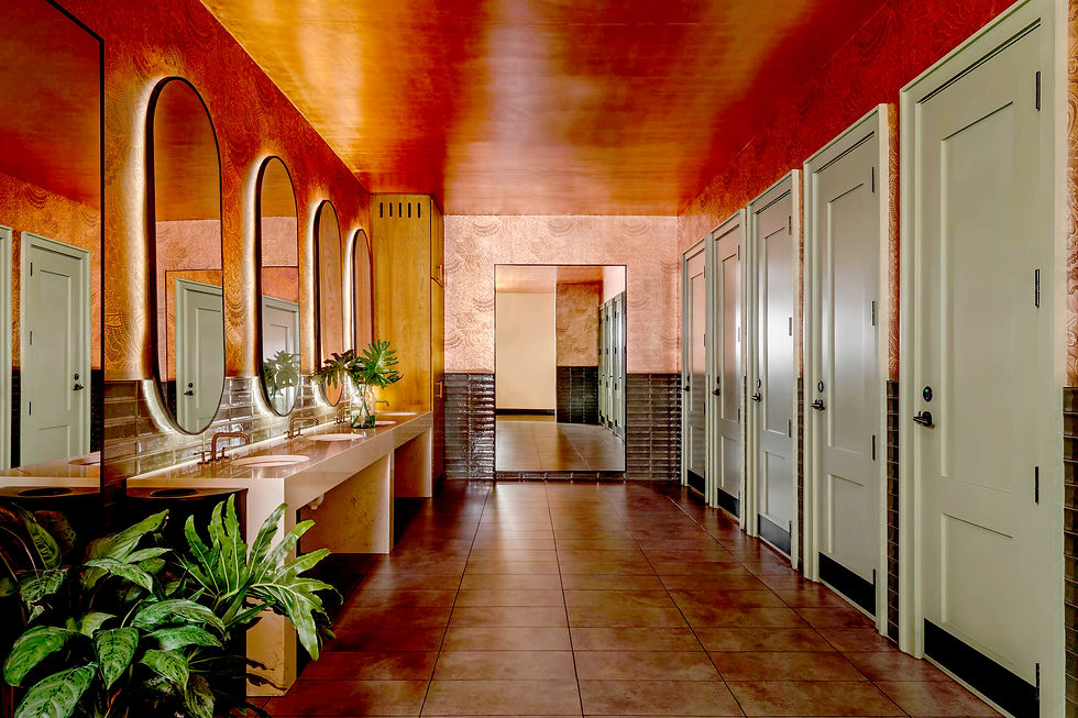 Reflective custom copper wallpaper on walls and ceiling in large restroom with plants and mirrors.
