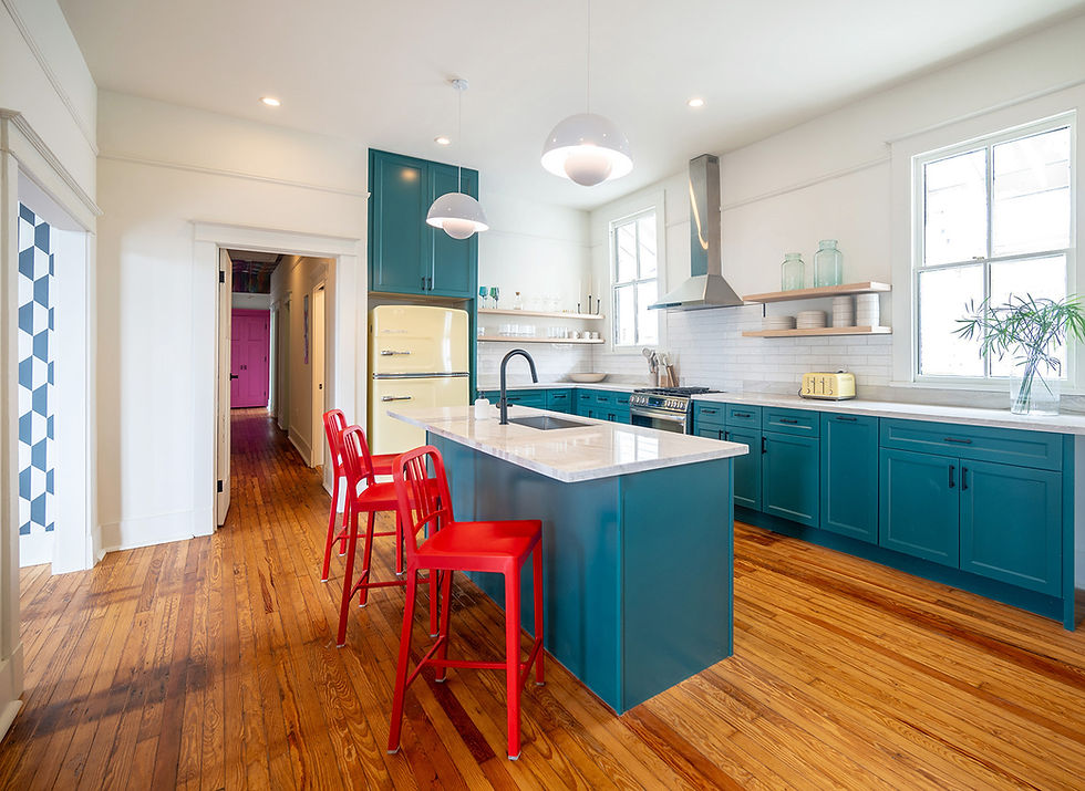 Kitchen with teal cabinets, vintage yellow refrigerator and red stools at the island