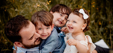un papa et ses 3 enfants dans un champ