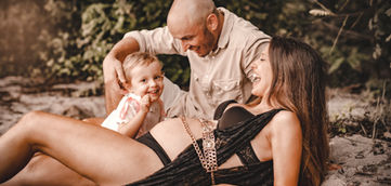 une femme enceinte sur la plage avec sa fille et son mari