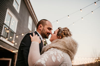 Bride and groom nuzzling noses with twinkle lights in background