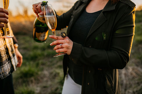 girl pouring champagne into glass with engagement ring