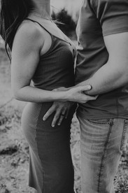 Black and white photo of couple holding baby bump