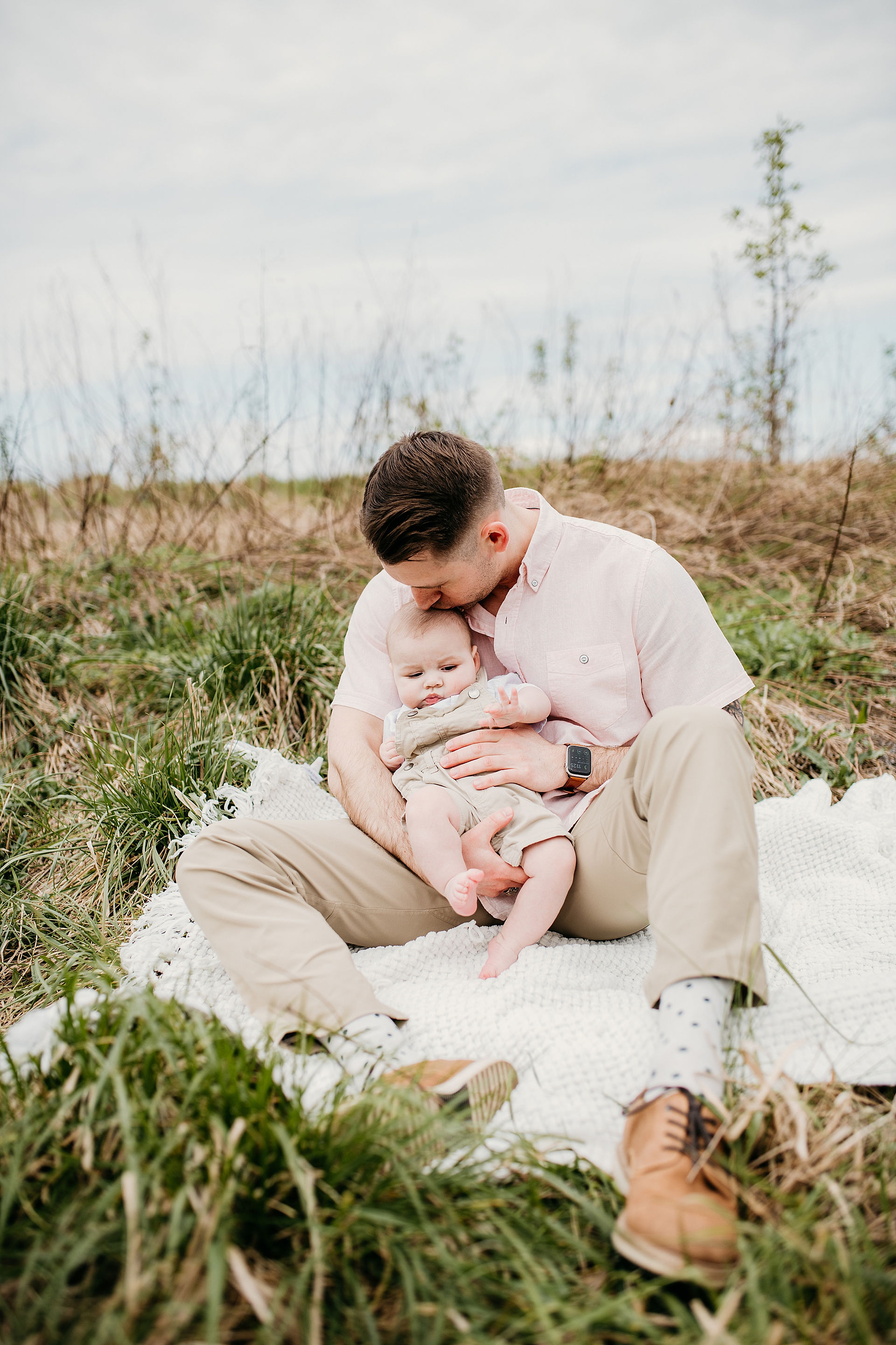 dad kissing baby on blanket