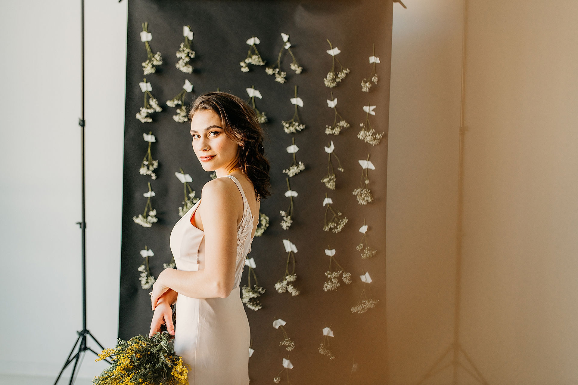 model standing looking back at camera holding yellow florals