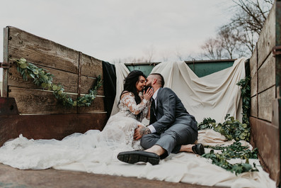 Bride and groom kissing in the back of truck bed