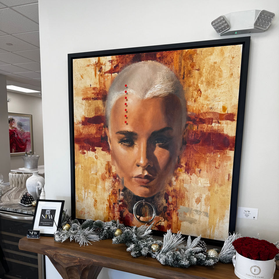 Striking portrait artwork displayed at Naples Fashion Week on 5th Avenue South in Naples, Florida. The piece features bold colors and a modern aesthetic, framed and showcased on a wooden console with festive decor. Artwork is from Shaw Gallery and is available for sale.