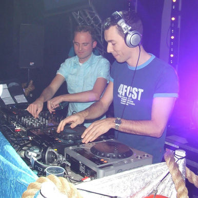 Dutch DJ and production duo Resolutions performing back to back at the decks in a club environment illuminated by blue and purple lighting.