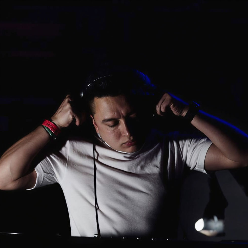 Colombian DJ and producer Morris Tellez adjusting his headphones during a performance, illuminated by low-key lighting against a dark club setting.