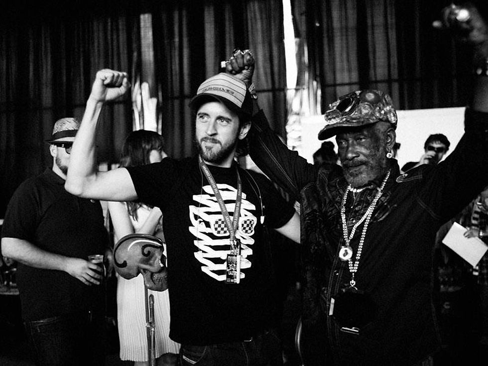 British DJ and producer Jstar with Lee 'Scratch' Perry at an event, black and white image.