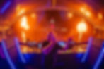 Electronic music artist Paul van Dyk performing on stage at a large festival crowd during a high-energy live show featuring flames, colourful lighting and an open-air arena atmosphere.