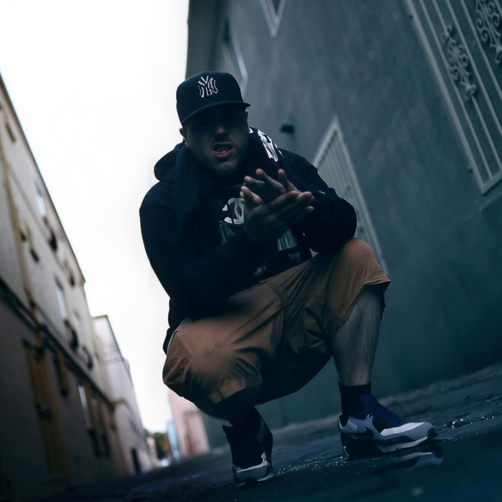 Johnny Slash crouching in an urban alleyway, wearing a cap, hoodie and shorts, with a low-angle perspective and moody lighting creating a gritty street atmosphere.