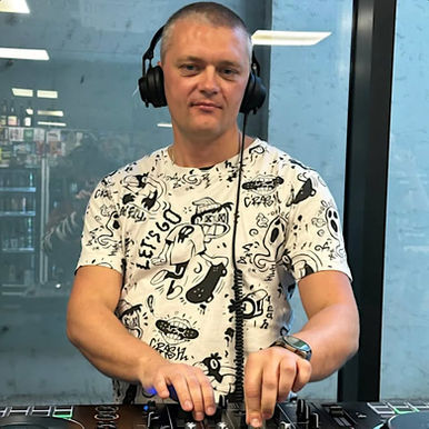 Ukrainian DJ and producer Trifonov S is performing at a bar event in Prague, Czech Republic, wearing Sennheiser HD25 headphones and smirking at the camera in a colorful image.