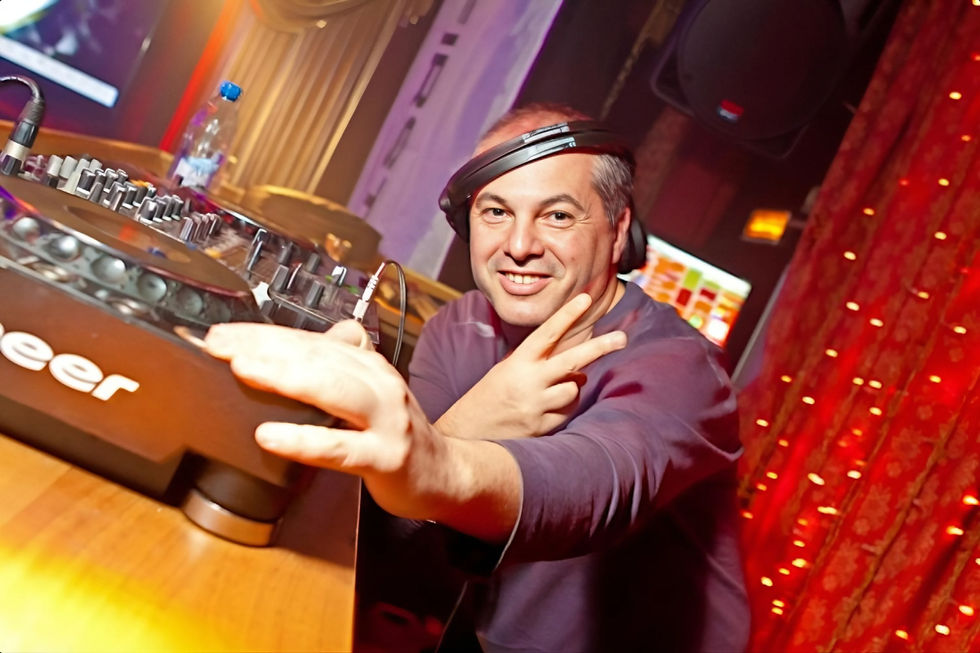 Italian DJ and producer Marco Mei performing at Rafinad Club, colour image taken at his left side at the level of the CDJs at a slight angle.