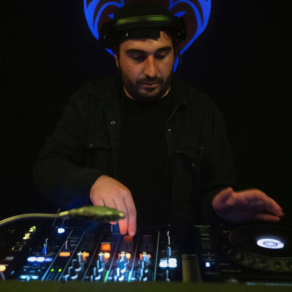 Don Creek performing on DJ equipment in a dark setting, wearing headphones and adjusting the mixer, illuminated by low, coloured lighting.