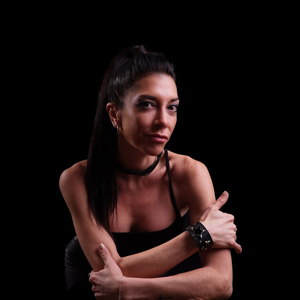 Argentinian DJ and producer Sabrina Rivas leaning forward on her forearm on a table in a studio image with a black background, colour image.