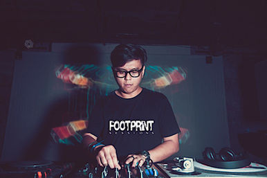 Malaysian DJ and producer Terence C is performing at Arkham in Shanghai, China, wearing a Footprint T-shirt. He is captured in a color image from the front, focused on the CDJs and mixer.