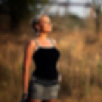 Colour portrait of DJ and producer Daria Fomina standing outdoors in warm sunset light, wearing a black top and skirt, eyes closed and facing the sun in a natural field setting.