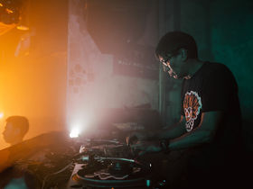 Singaporean DJ and producer Brendon P performing at Kilo Lounge, captured in a side profile from his left, with the dancefloor visible in front of him in a vibrant colour image.