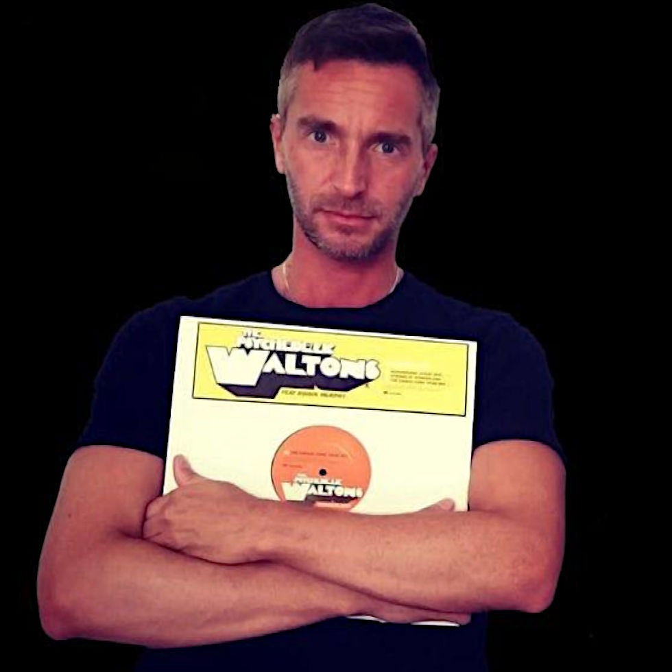 Italian DJ and producer INVE standing with his arms ccrossed holding a vinyl record to his chest, colour image.