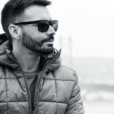 Spanish DJ and producer Zeleon, standing wearing a puffer jacket and sunglasses, looking to his left in a black and white image.