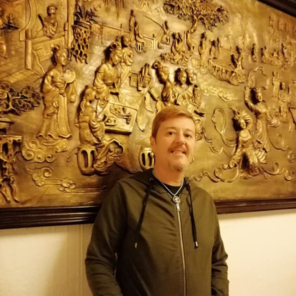 Italian DJ and producer El Brujo standing against carved picture in gallery, colour image.