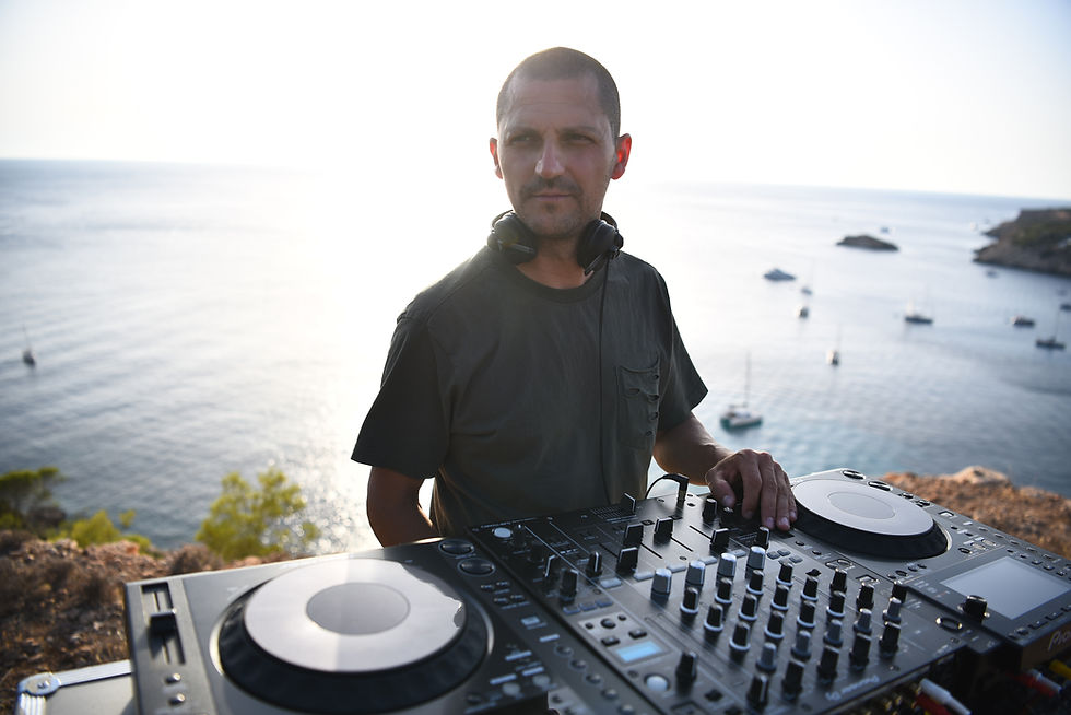 Italian DJ and Producer MaurizioG performing at a seaside resort on a sunny day overlooking the bay, colour image.
