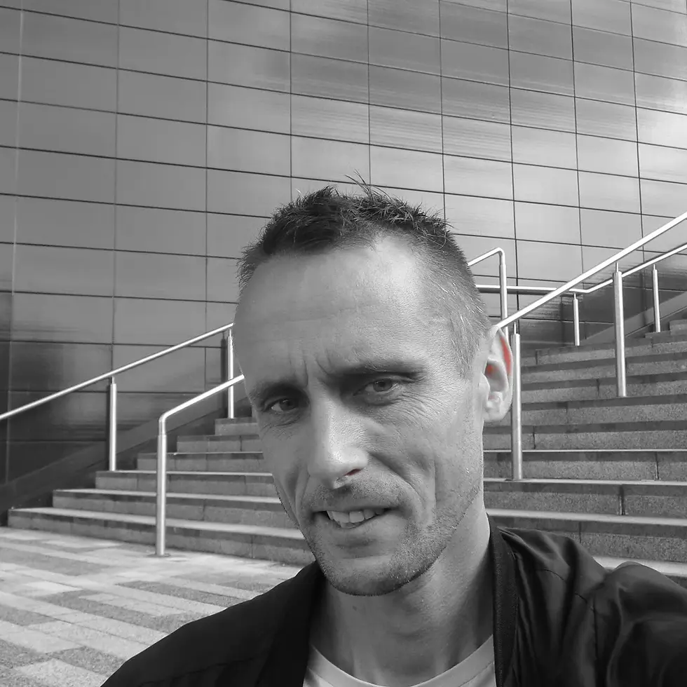 British DJ and Producer Kev Willis standing on a stairway to a building, black and white image.