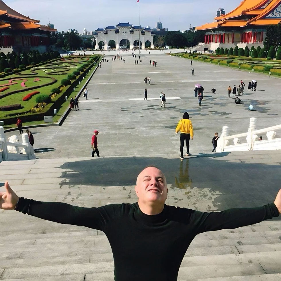 Marco Mei, Italian DJ and producer, arms outstretched at the top of the steps overlooking Liberty Square at Chiang Kai-shek Memorial Hall in Taipei, Taiwan.
