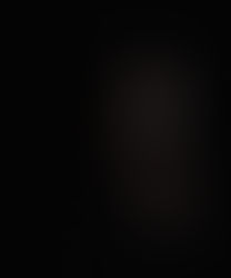 Indonesian DJ Yorri in dark room right side of face showing with right hand on left cheek, colour image.