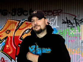 French DJ and videographer DJ Pheonixx standing in front of a graffiti wall in Ziele, Germany, colour image by Thomas G. from Pixabay
