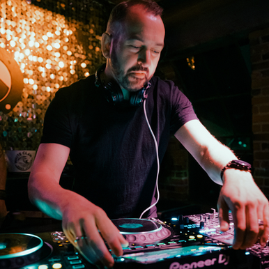 British-American DJ and producer Paul Velocity performing at a nightclub on Pioneer CDJs and a Mixer, colour image.