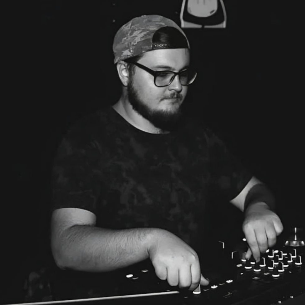 Black-and-white image of Andrés Moris wearing glasses and a backwards cap while adjusting controls on a DJ mixer, representing the Córdoba, Argentina DJ and producer known for Progressive House.