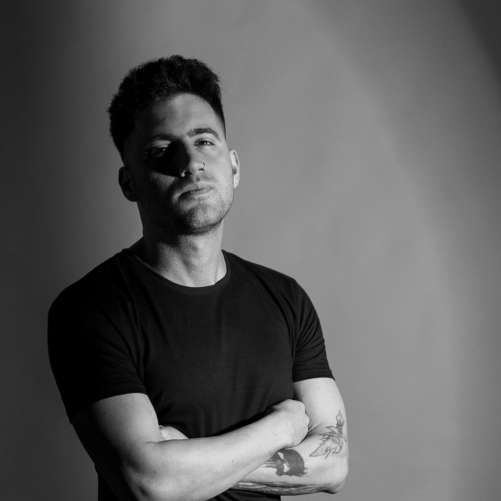 Argentinian DJ and producer Lisandro Restaino standing with his right shoulder facing forward with his arms crossed, black and white image.