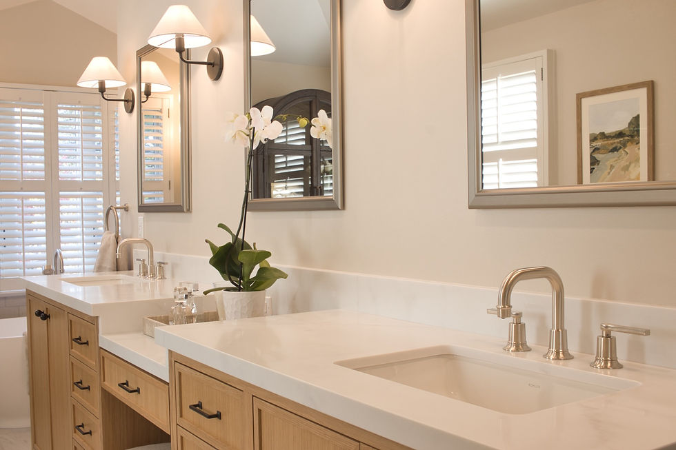 Elegant bathroom with dual sinks, wooden cabinets, and silver faucets. Orchid plant and mirrors under soft lighting. White shutters and art.