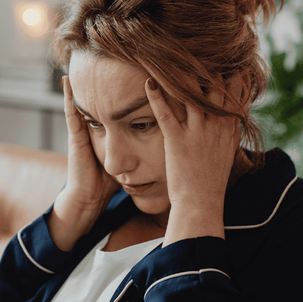 woman holding her head, looking down, frowning slightly