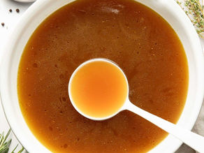 bowl of warm brown bone broth with a spoon