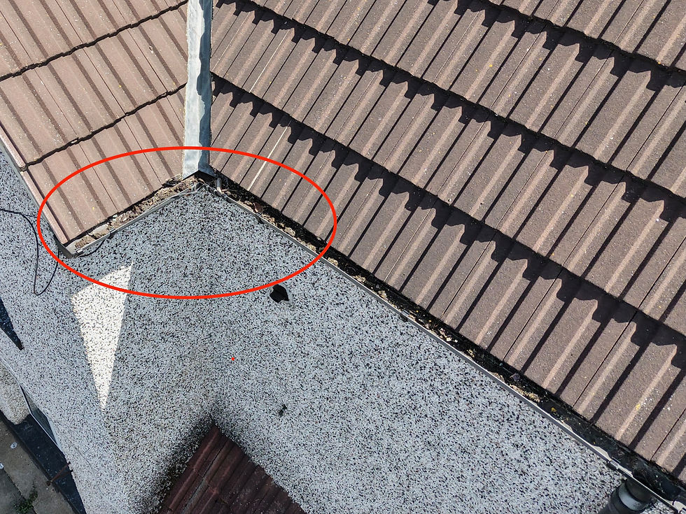 Aerial view of a brown tiled roof with a red oval highlighting damaged flashing at a roof corner near a chimney.