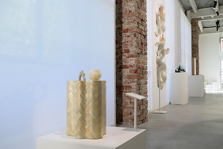 A sculptural straw marquetry side table exhibited milan design week