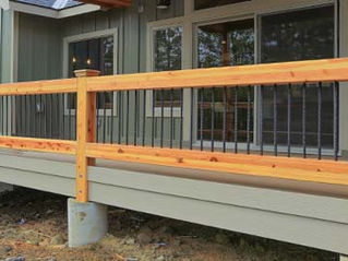 Newly built home featuring a cedar railing and black balusters.