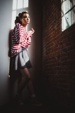 Sad girl in red and white stripped sweater looking wistfully out a window
