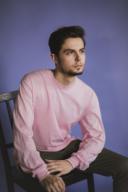 Man in pink sweater against purple background