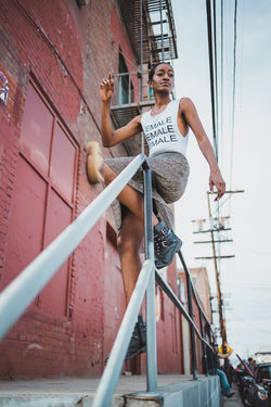 Girl wearing fashionable clothes leaning over railing in downtown Los Angeles