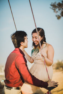 Man pushing girl on swing