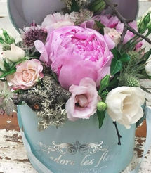 Boite à chapeau bleu pastel avec composition florale au centre dans les tons rose et blanc